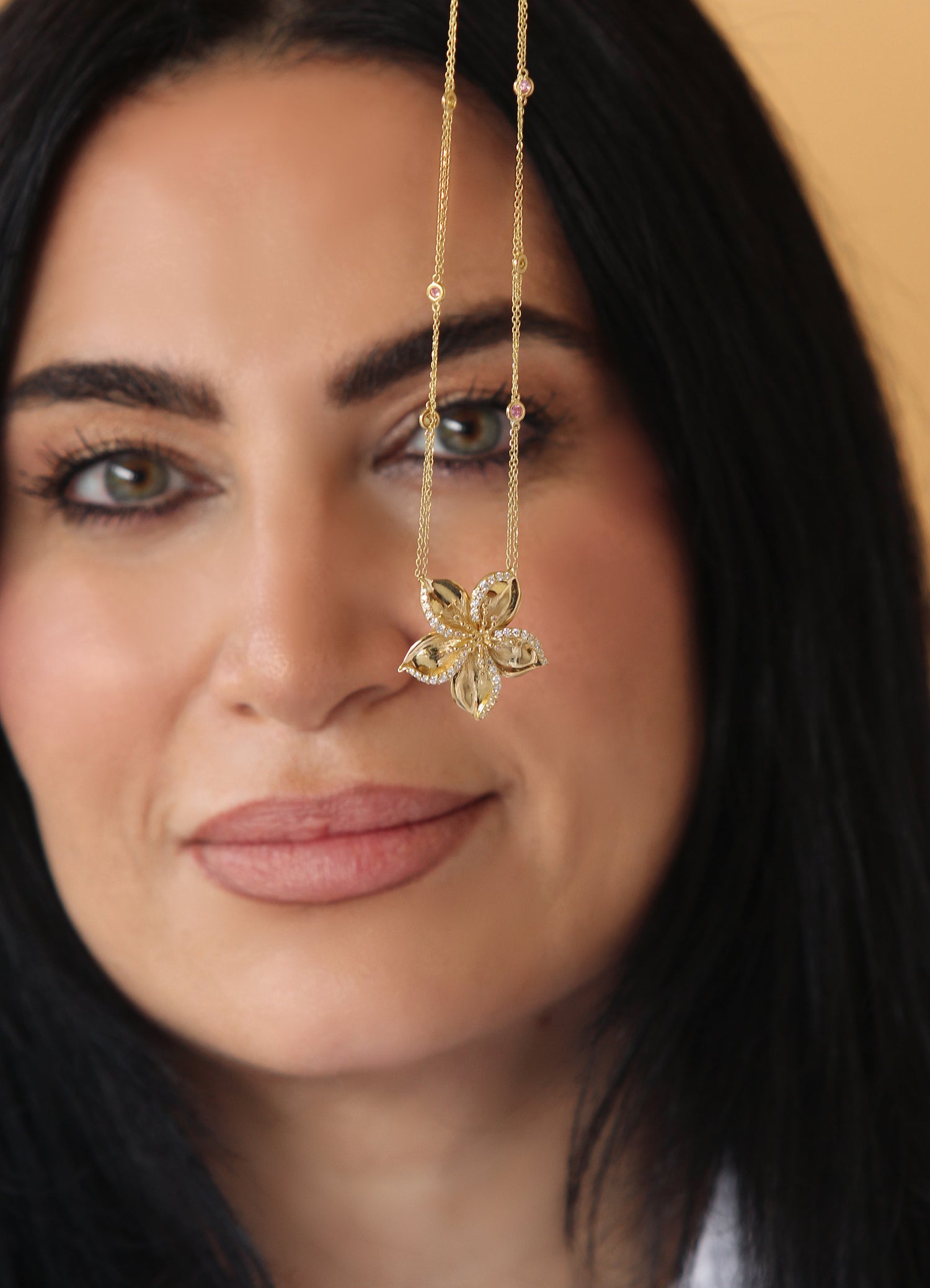 Woman holding gold Frangipani Necklace designed by Renée Chamoun